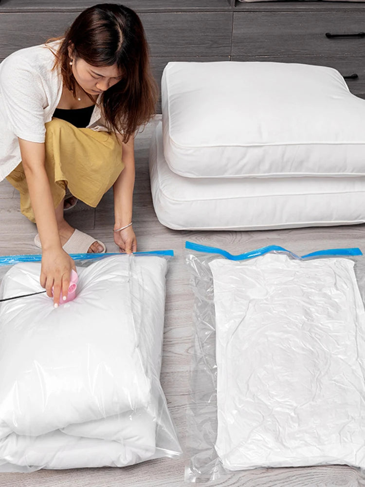 Woman vacuum sealing white pillows and bedding in transparent storage bags on wooden floor