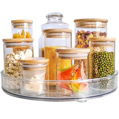 Clear glass jars with bamboo lids storing various dry foods on a clear rotating tray