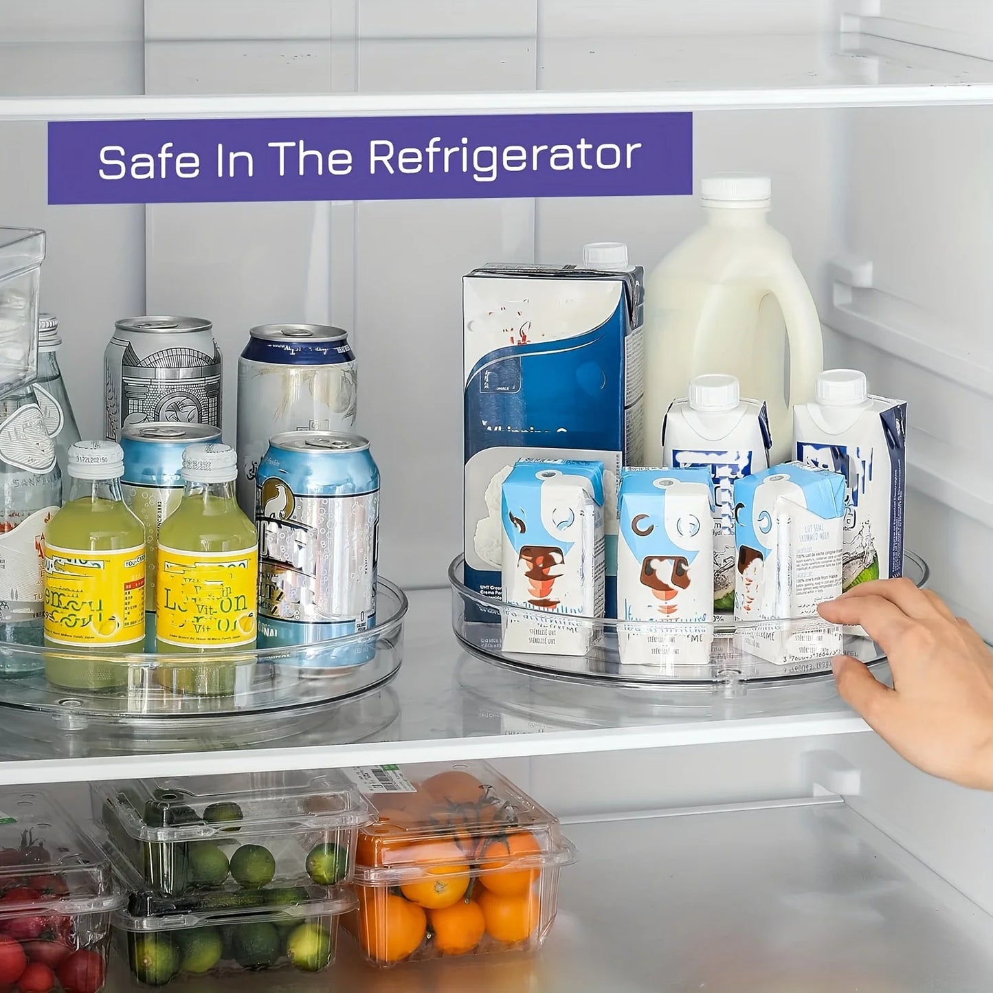 Hand reaching into refrigerator with rotating clear trays holding assorted drinks and cartons, fresh fruits below