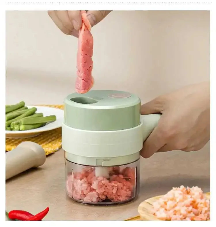Hand using electric mini food chopper to mince raw meat on kitchen table with vegetables