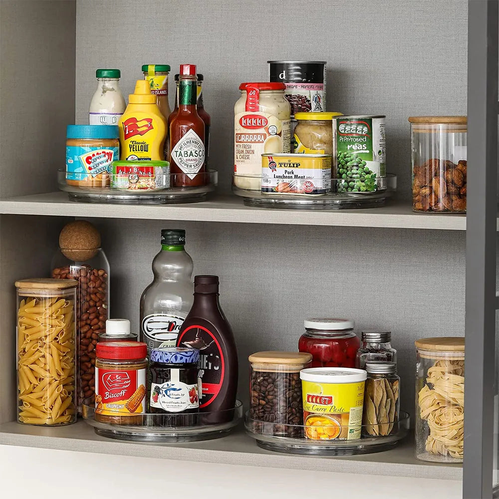 Kitchen pantry shelves with assorted condiments, canned goods, pasta, nuts, and jars on clear Lazy Susan organizers