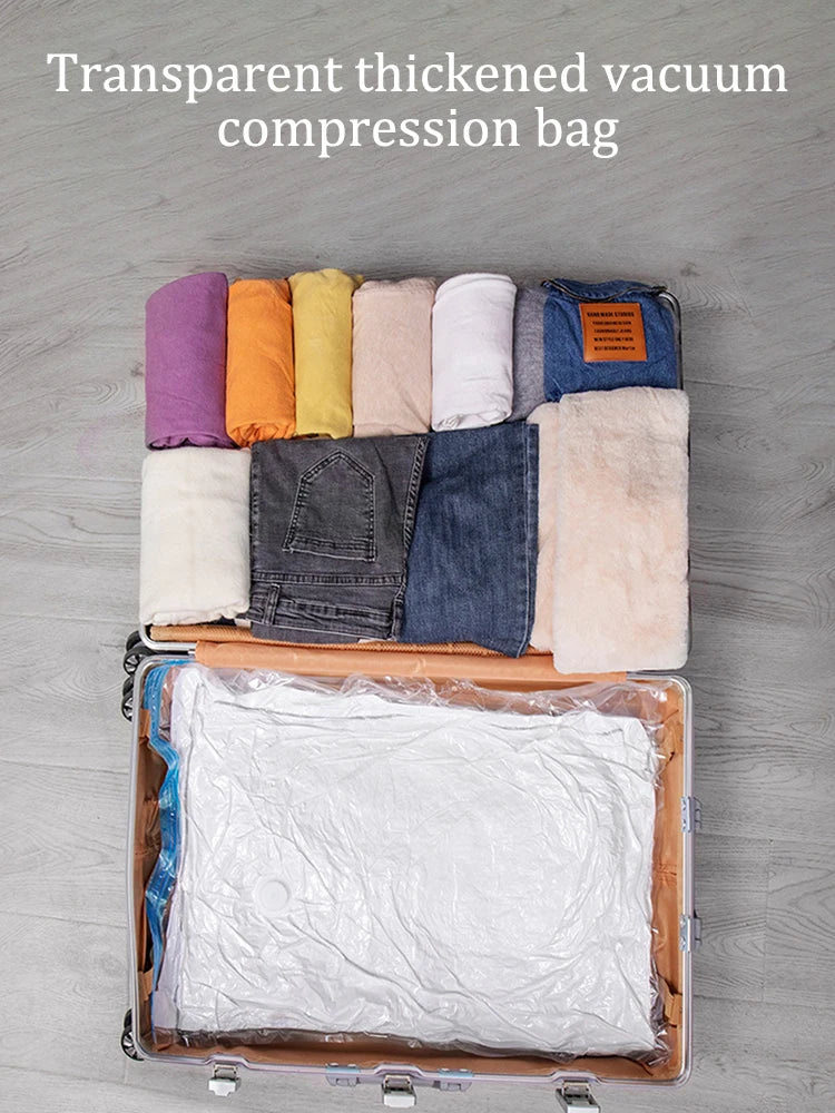 Open suitcase with folded clothes and a transparent thickened vacuum compression bag on a grey wooden floor