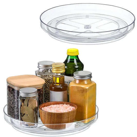 Clear plastic lazy Susan turntable with assorted spice jars, seasoning bottles, and a wooden bowl of pink salt