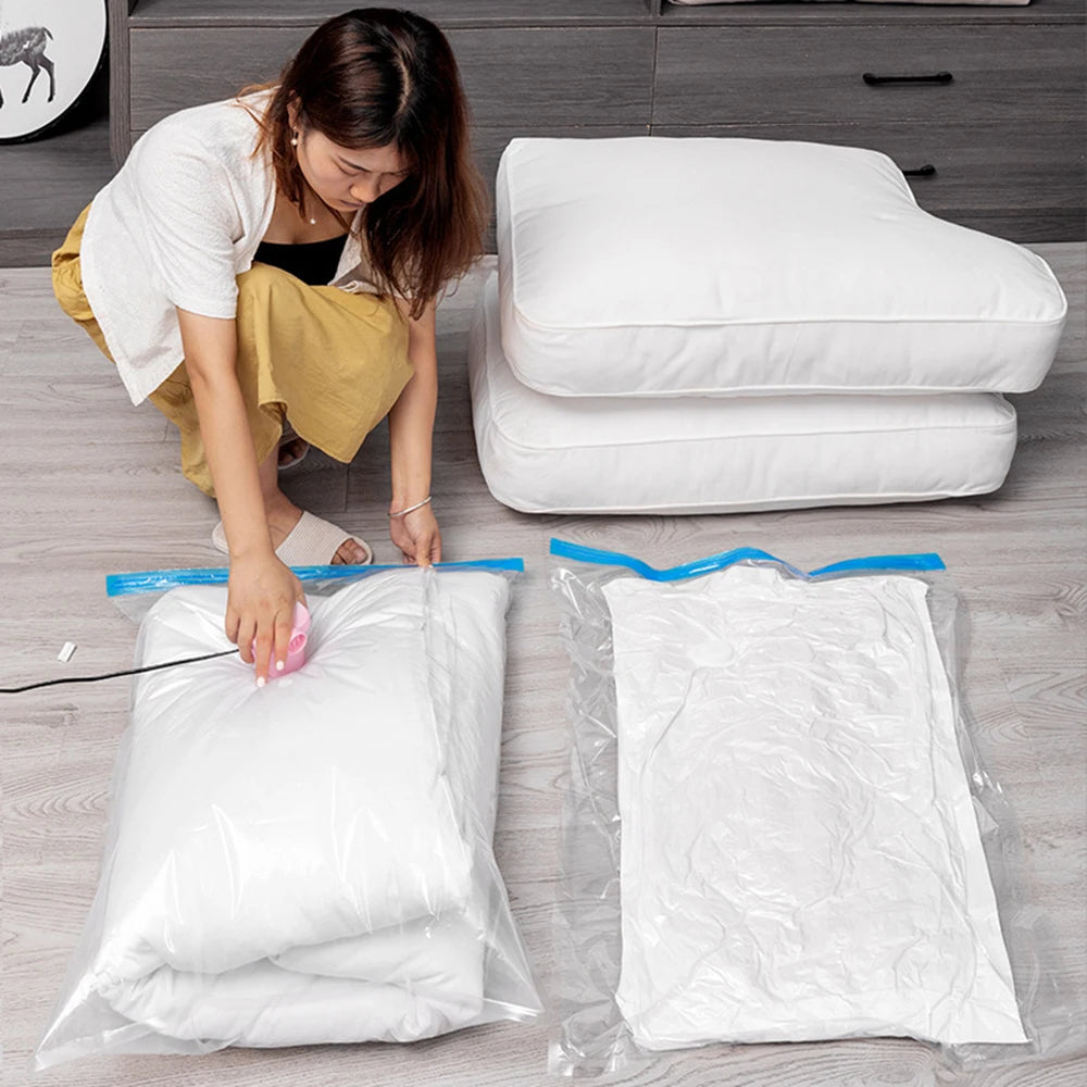 Woman using a vacuum pump to compress white bedding in vacuum storage bags on a wooden floor